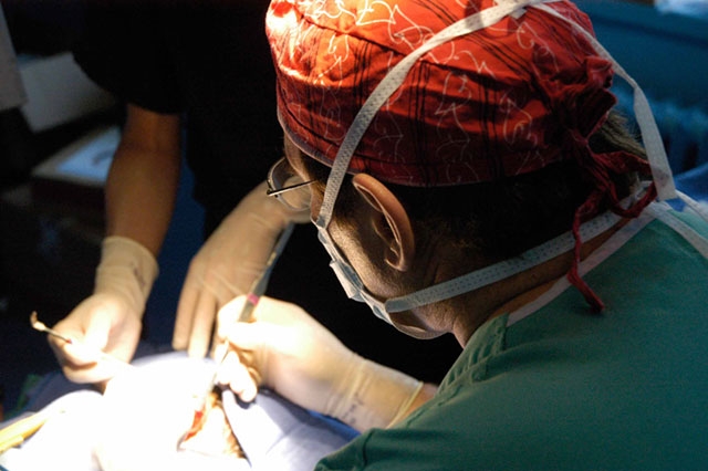 Close-up of what appears to be a surgical procedure, showing hands in surgical attire.