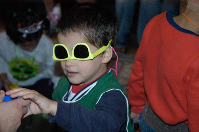 A young child wearing novelty sunglasses, possibly at a party or special event.