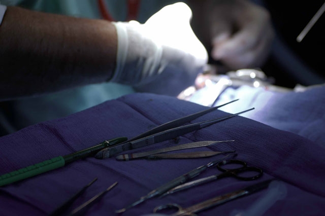 Hands working on what seems to be a surgical procedure under focused light.
