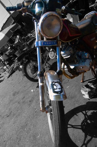 A motorcycle or similar vehicle photographed from the front, showing the headlight and handlebars.