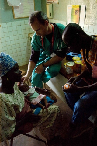 Several people in what looks like a medical or healthcare setting with tiled walls, possibly showing healthcare workers attending to patients.