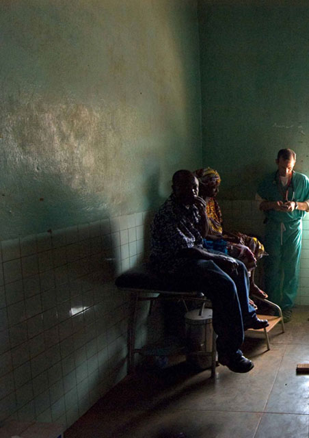 Two people sitting in what looks like a dimly lit interior space with a beam of light creating shadows.