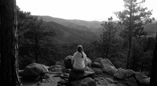 A black and white landscape photograph showing what appears to be a person in a natural setting.