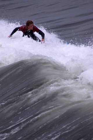 A surfer riding a large wave with white spray.