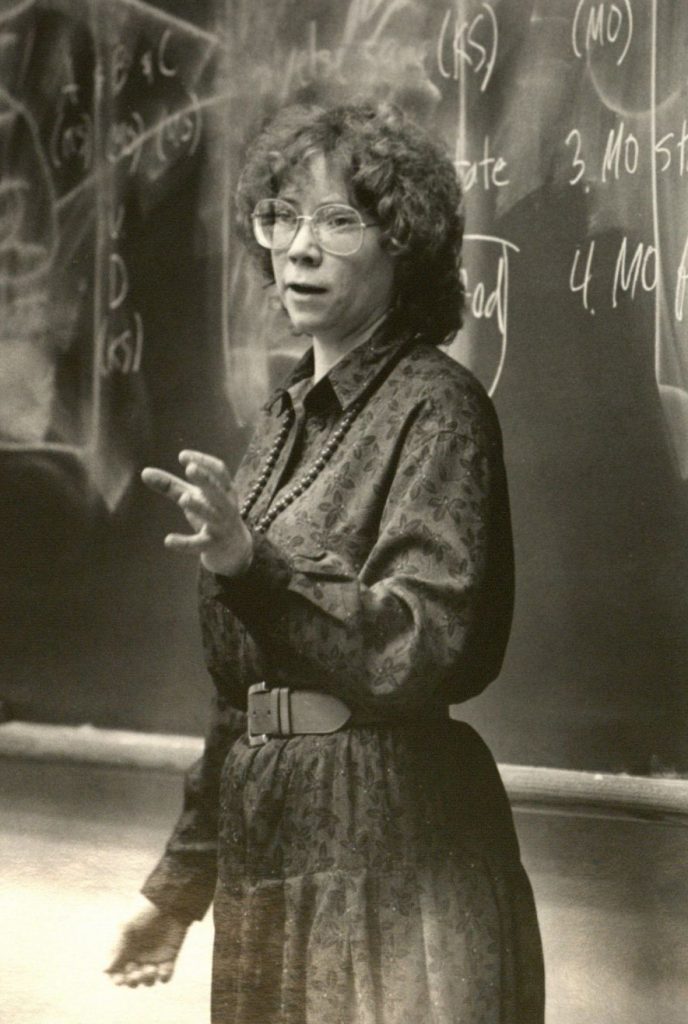 Black and white image of Ellen Sward in front of a chalkboard