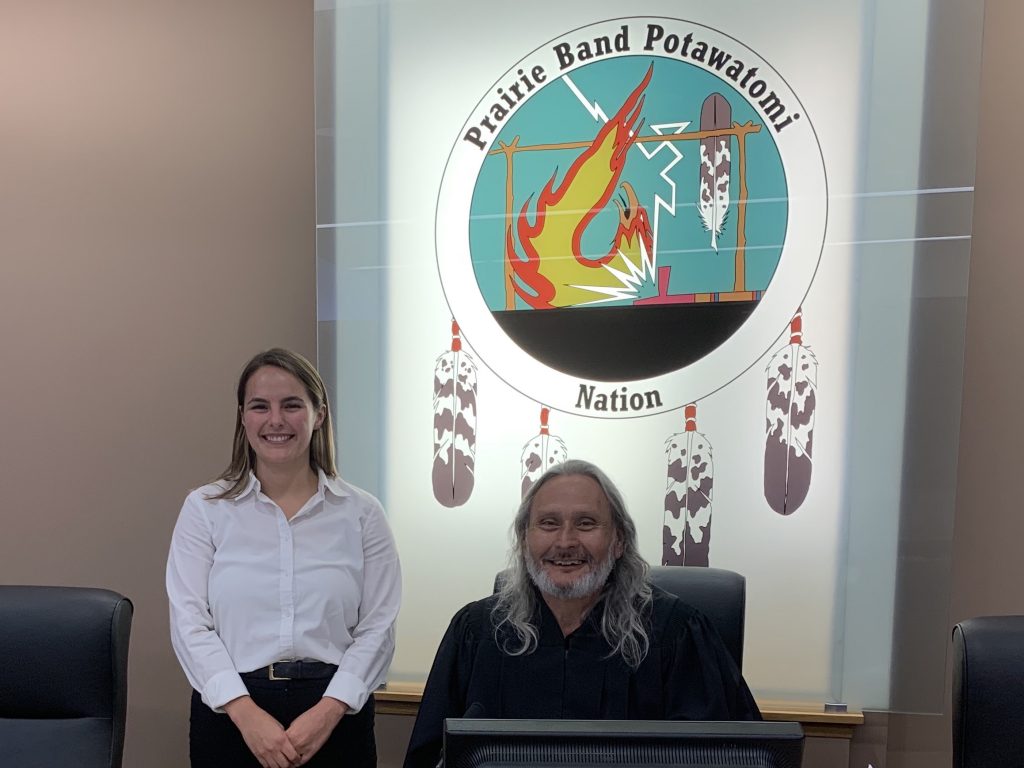 Aidan Graybill standing with Charles H. Tripp in front of a sign that says 'Prairie Band Potawatomi Nation'