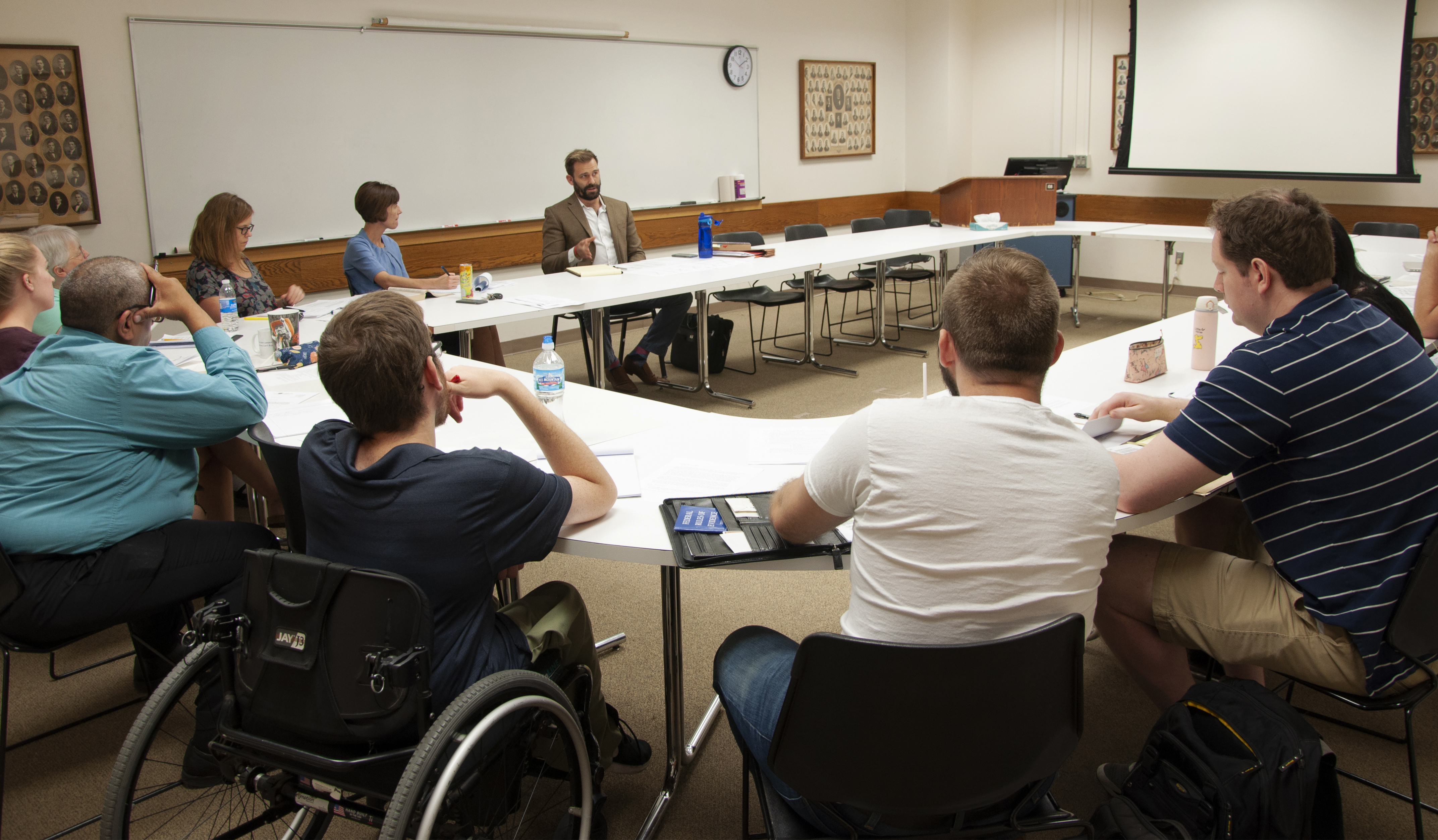 Bill Walberg and a group of students seated at tables arranged in a rectangle