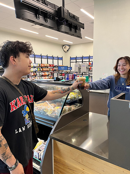A barista hands a drink to a student