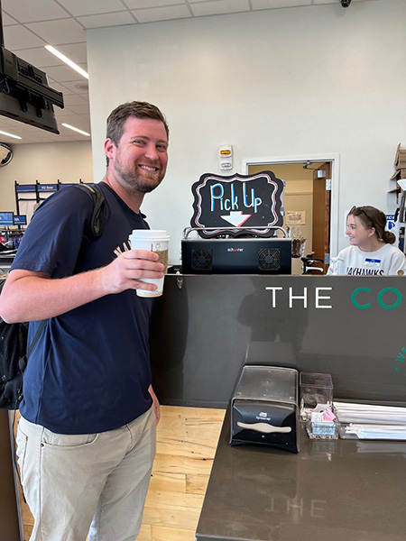 a man smiles with a cup of coffee