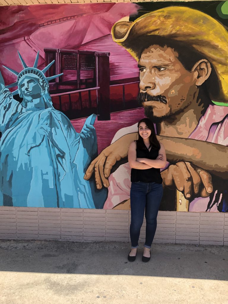 Claudia Chavarria standing in front of a mural