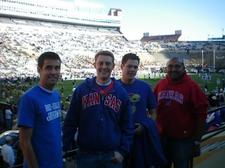 Four men smiling while at a football game.