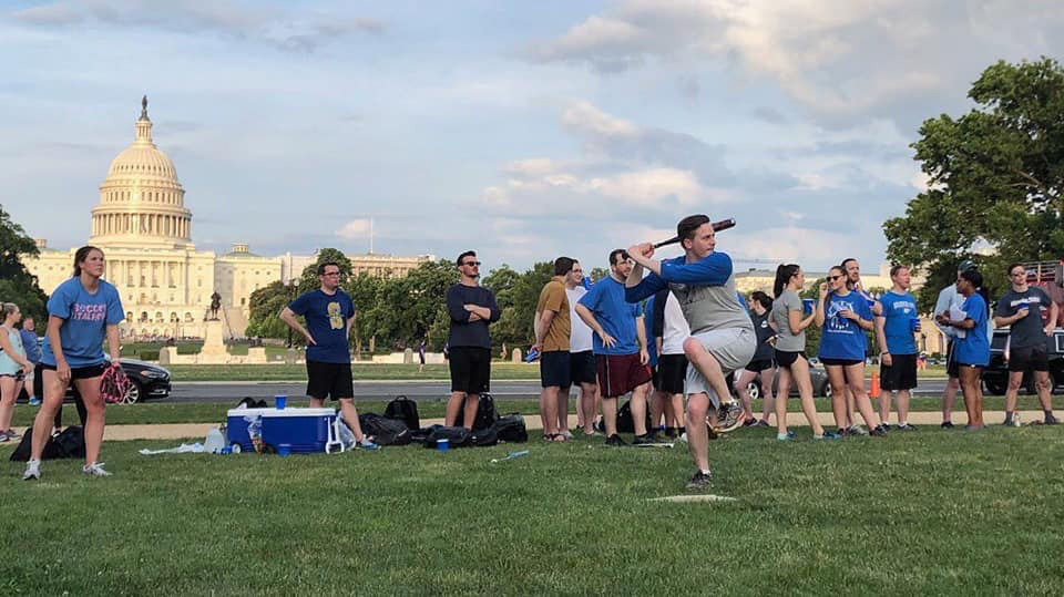 A softball game on a lawn with the US Capitol in the background