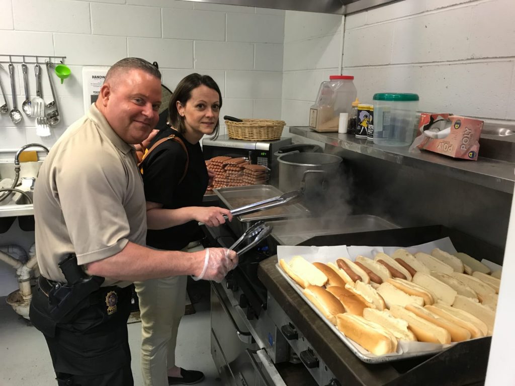 A man and a woman cooking hotdogs