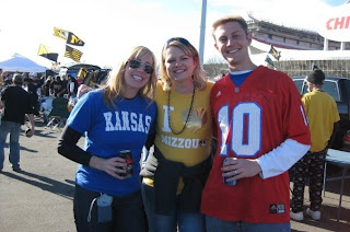 Three people tailgating outside a stadium