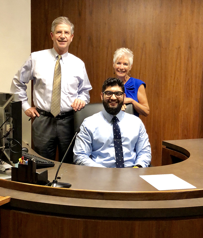 Omar Husain sitting at a desk with Paul Gurney and Arleen Schuman