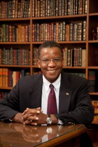 Reggie Robinson smiling in front of bookshelf wall
