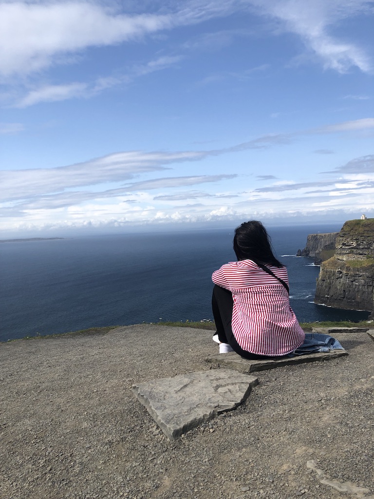 A woman sitting on the Cliffs of Moher in Ireland