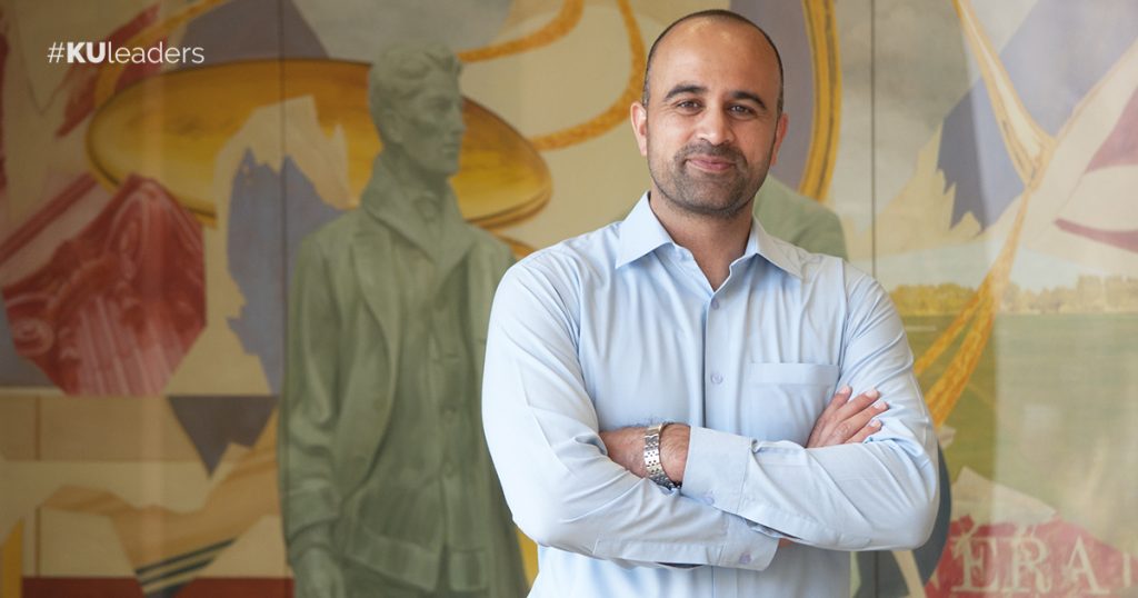 Dr. Bakht Munir in front of a mural