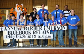 A group of people holding up a sign that says 'Annual Barber Emerson Bluebook Relays'