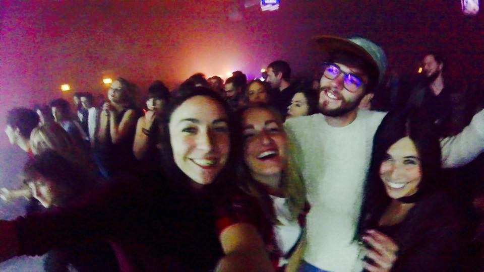 Friends in a dark nightclub with bright lights.