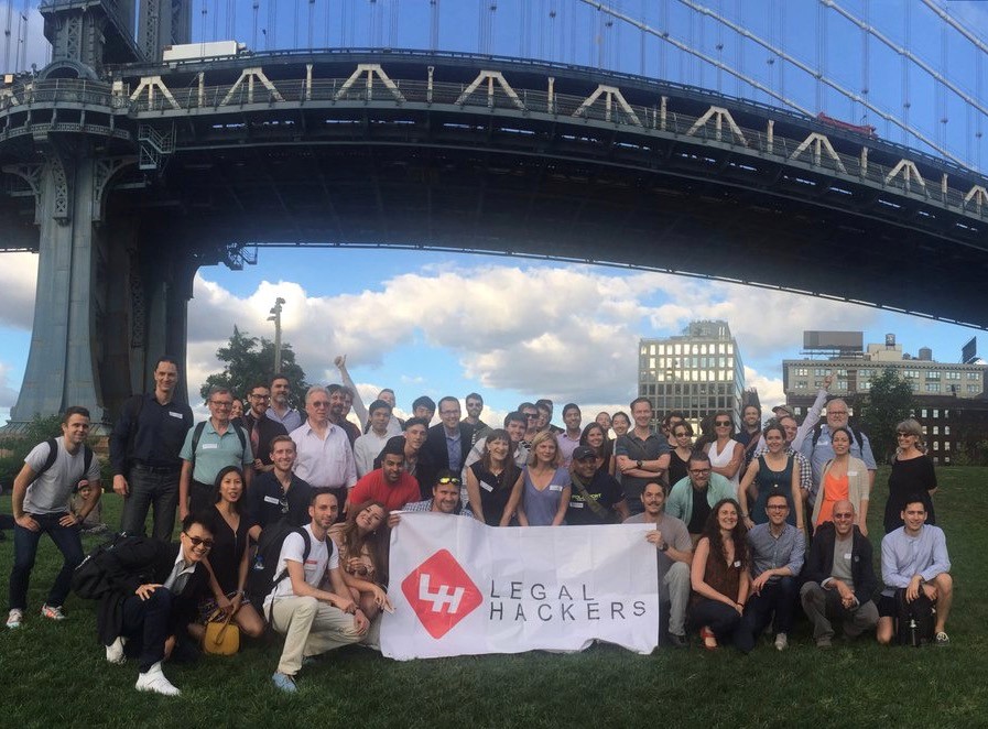Group of people posing around Legal Hackers banner in front of bridge