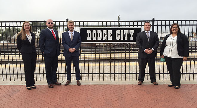 Jonathan Ehrlich and 4 colleagues next to a sign on an iron fence that says 'Dodge City'.