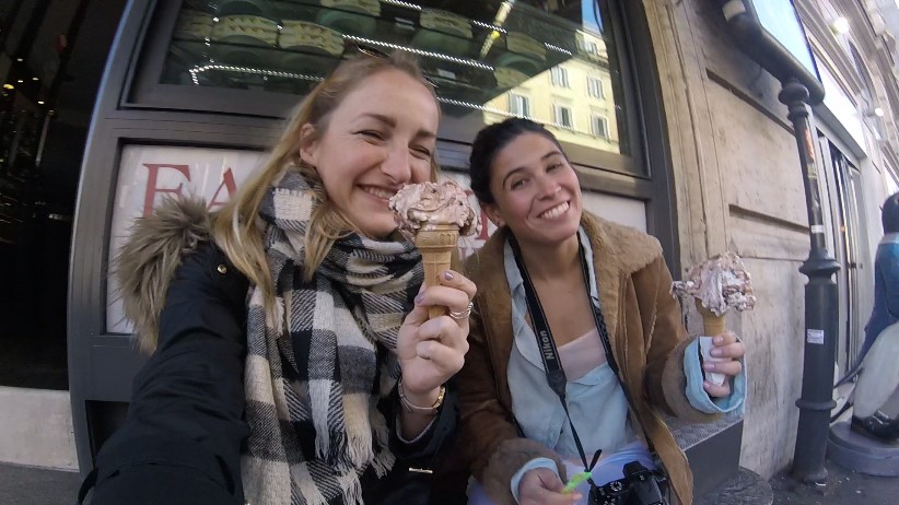 Two students in winter coats eating gelato.