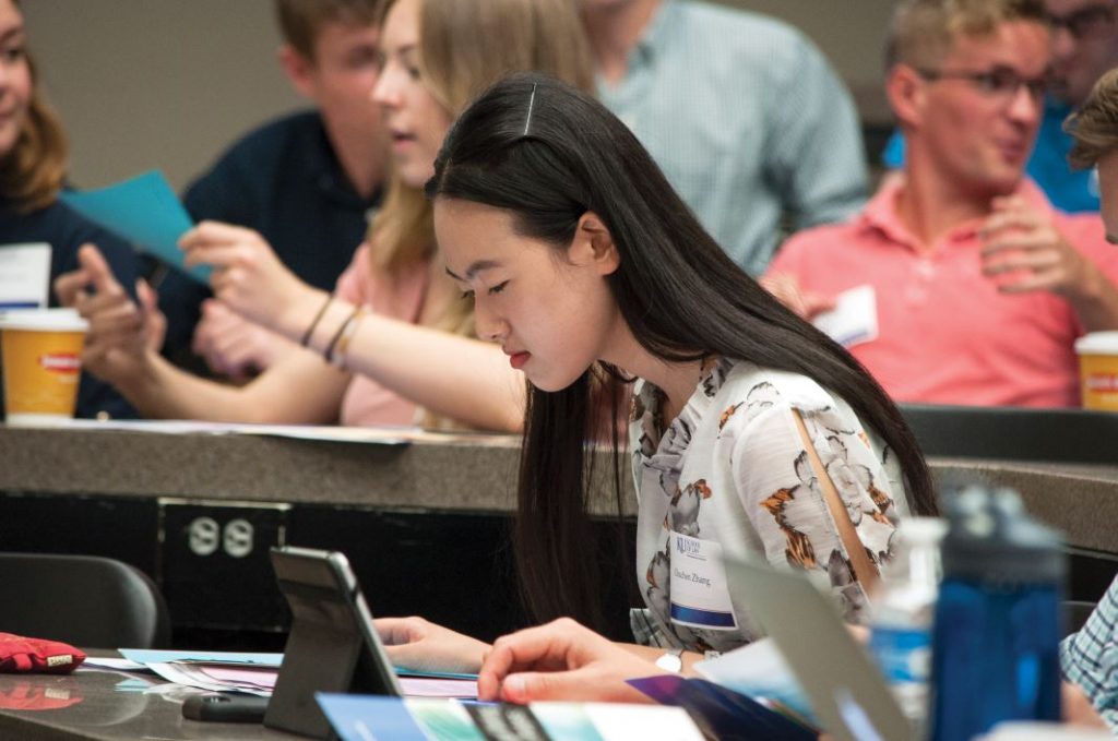 A student sitting in class and looking at their Ipad