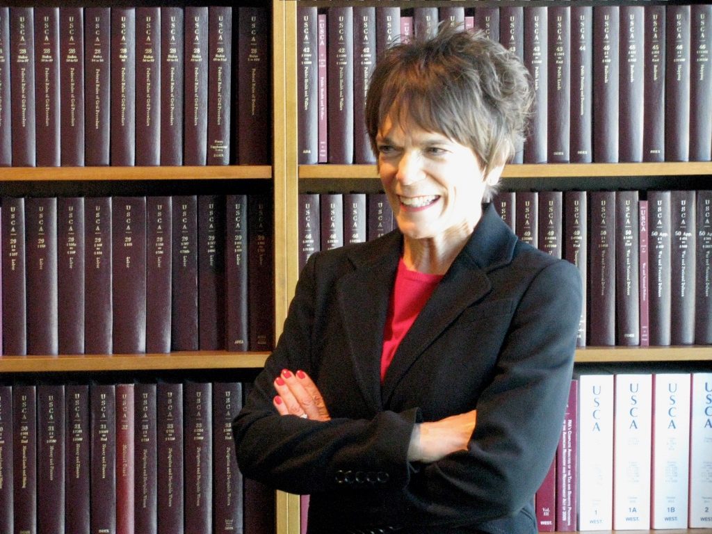Jan Sheldon in front of a bookshelf full of legal books