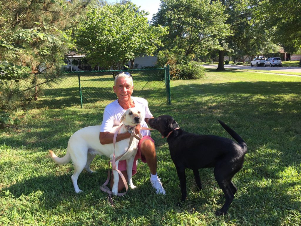 Jeff Montgomery on a grass lawn with two dogs