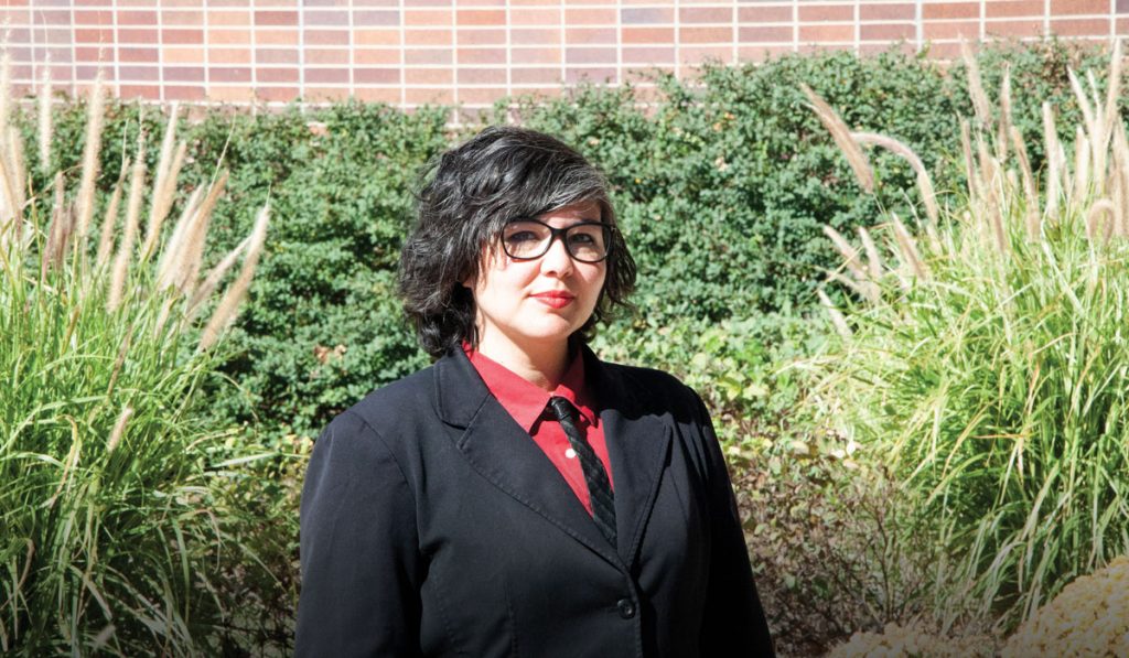 Jennifer Ananda in front of plants and a brick wall