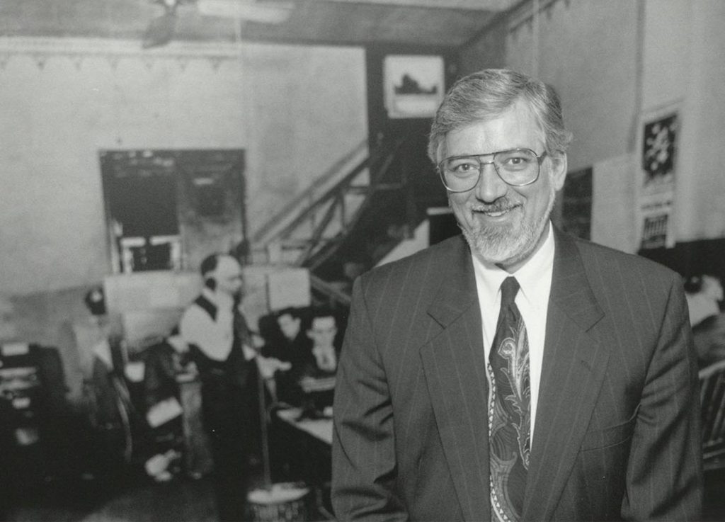 Kautsch in front of a mural made from a historic photograph of the Emporia Gazette newsroom.
