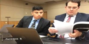 Kevin Salazar looks at exhibits with the prosecuting attorney during a trial, in a screencap from the live court feed.