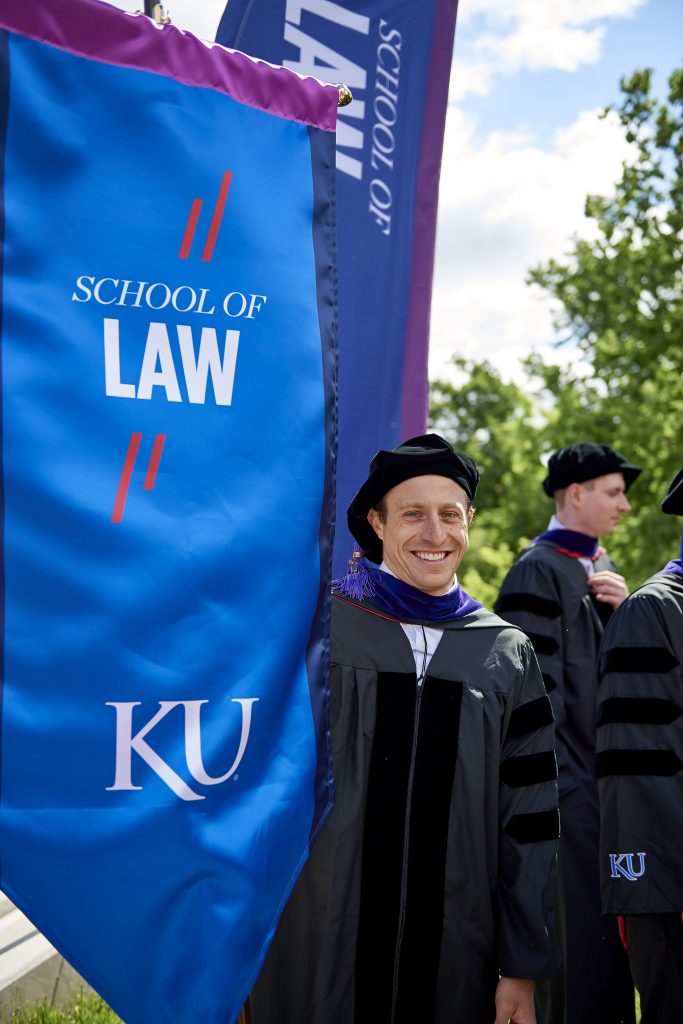 KU Law banner carrier Michael Hayes graduated with both a J.D. and a Ph.D. Photo by Earl Richardson Photography.