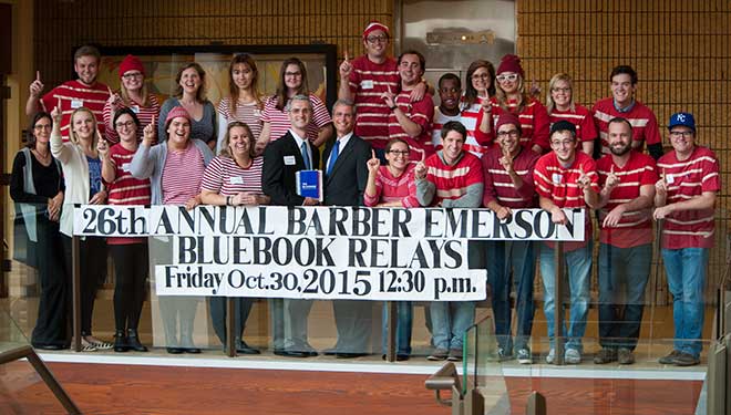 Group of people holding a sign about 26th Annual Barber Emerson Bluebook Relays