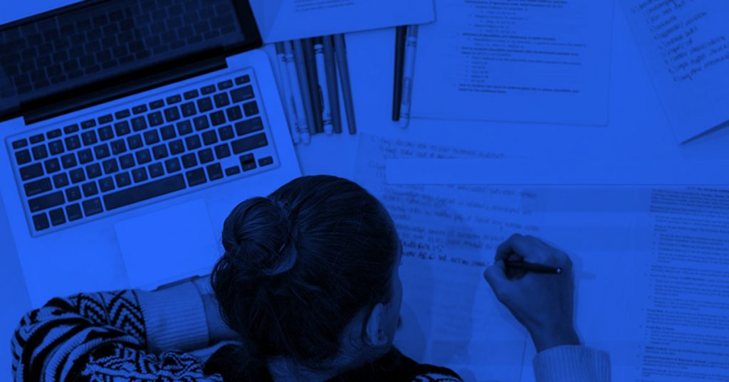A top-down view of a student studying at night with a blue light covering the room.