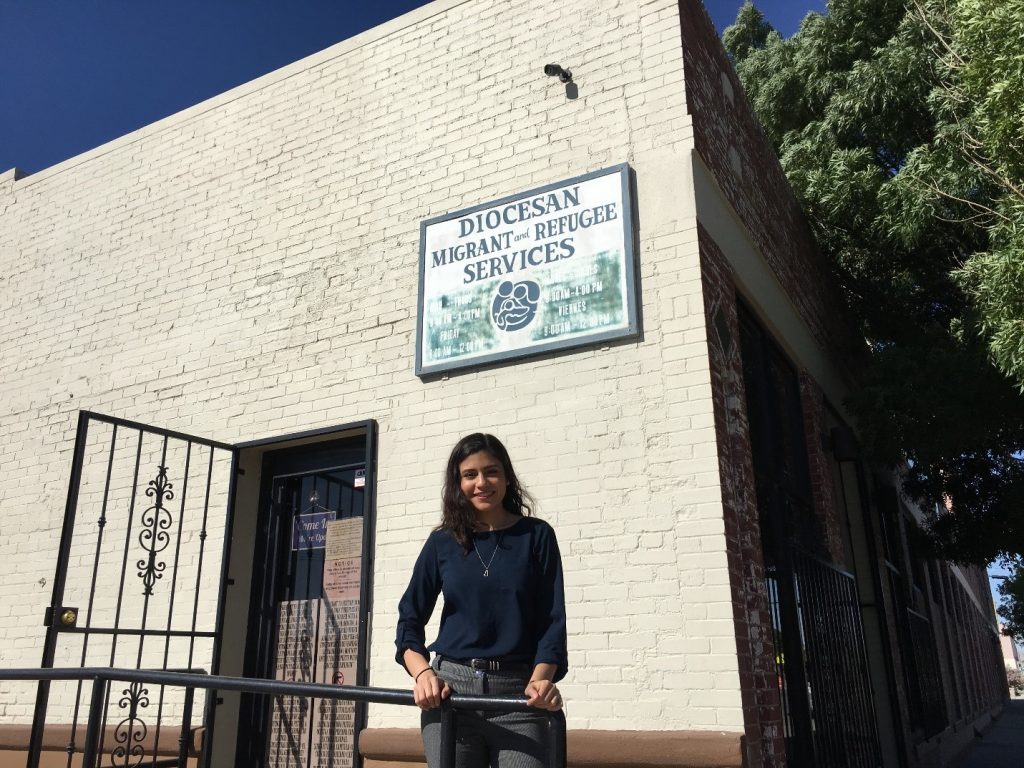 Samantha Natera in front of building with 'Diocesan Migrant and Refugee Services' sign