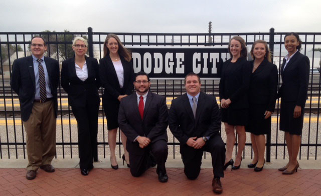 People in suits next to a sign saying Dodge City