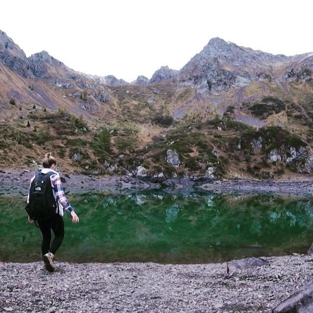 Miranda hiking alongside water and mountains.